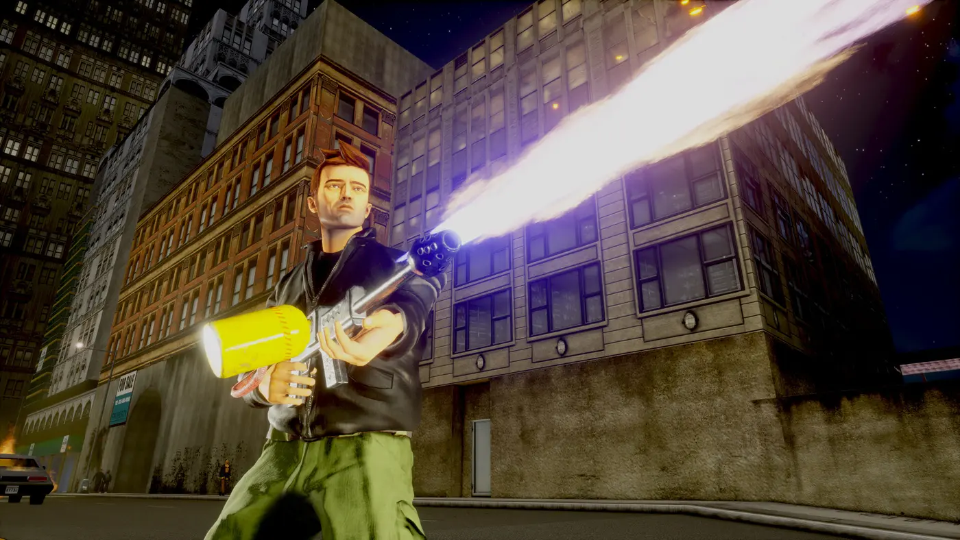 Claude en blouson de cuir et pantalon cargo vert tire un long jet de flammes avec un lance-flammes dans une rue de Liberty City la nuit, immeubles de brique et gratte-ciels autour