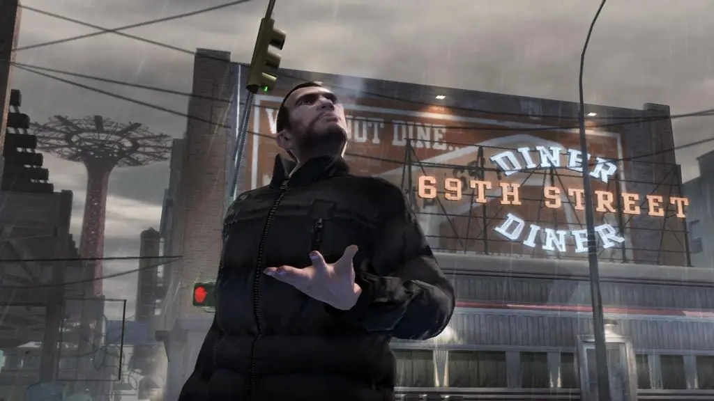Niko Bellic en blouson noir lève les yeux sous la pluie dans une rue de Liberty City, enseigne lumineuse du 69th Street Diner et grande roue au loin