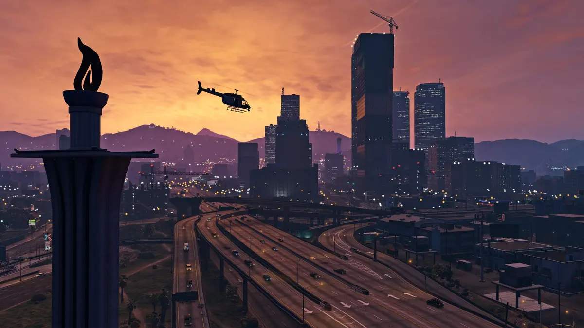 Panorama de Los Santos au crépuscule dans GTA 5, gratte-ciel du centre-ville, un hélicoptère survole l'autoroute, ciel orangé