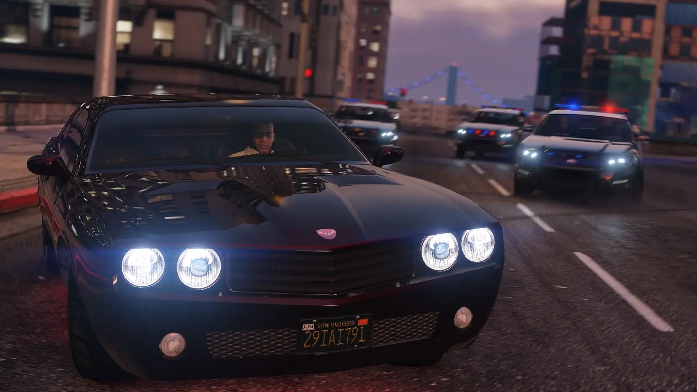 Franklin au volant d'une muscle car noire poursuivi par plusieurs voitures de police gyrophares allumés, dans une rue de Los Santos au crépuscule avec gratte-ciels et pont suspendu à l'arrière-plan, dans GTA V