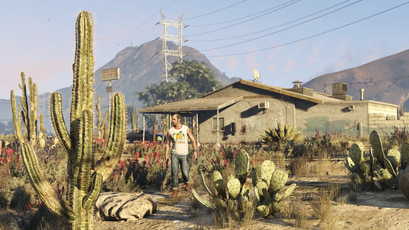 Trevor, l'un des protagonistes de GTA 5, marche dans un désert de cactus près d'un diner, une montagne en arrière-plan