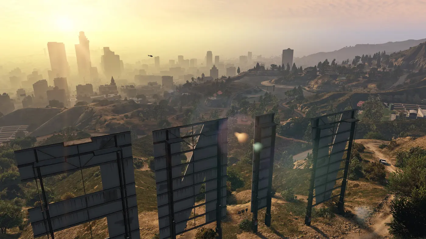 L'arrière du gigantesque panneau Vinewood sur une colline, face à la silhouette du centre-ville de Los Santos dans une brume dorée