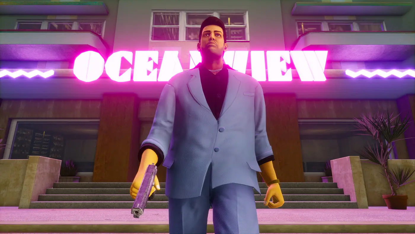 Tommy Vercetti en costume clair, pistolet à la main, devant l'enseigne néon rose « Ocean View » d'un hôtel Art déco de nuit, dans GTA Vice City