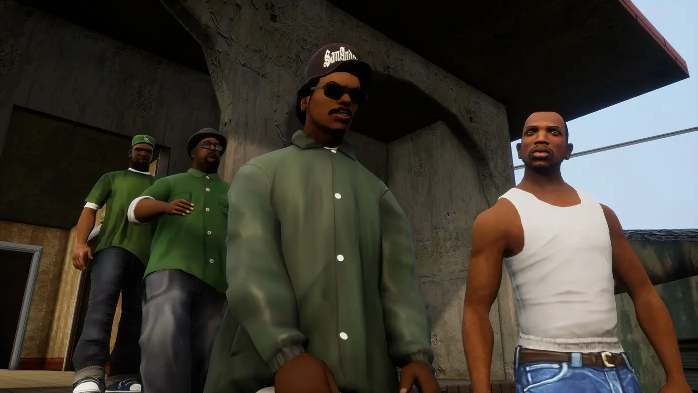 Carl CJ Johnson en débardeur blanc à droite, aux côtés de trois membres des Grove Street Families en tenues vertes, devant un mur de béton dans GTA San Andreas Definitive Edition