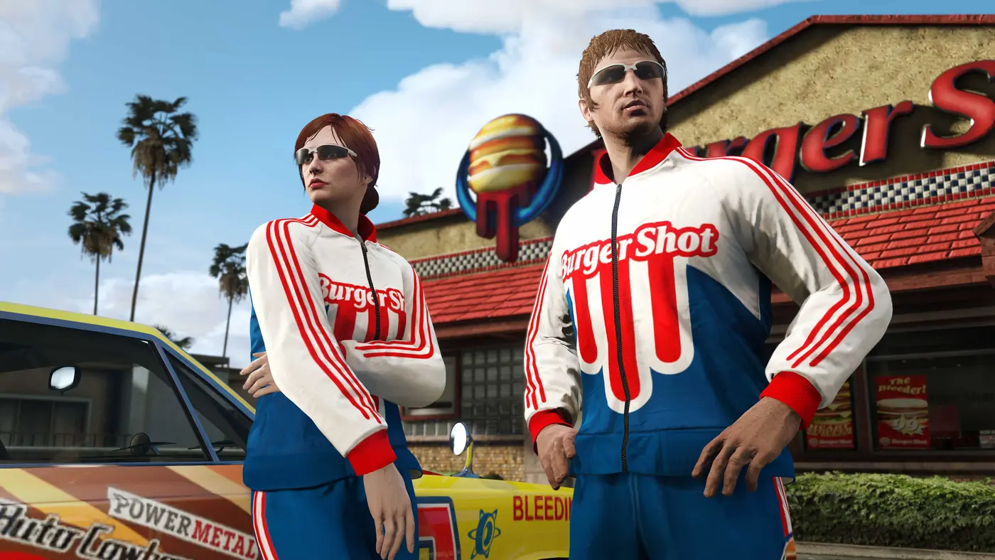 Deux personnages de GTA Online en survêtement Burger Shot rouge, blanc et bleu, lunettes de soleil, debout devant un fast-food Burger Shot avec palmiers et voiture de course jaune, ciel bleu