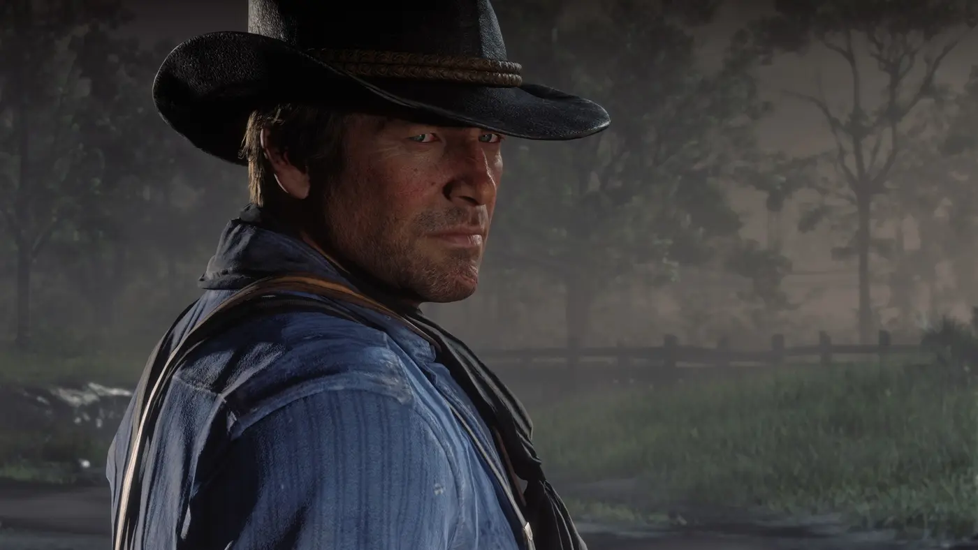 Gros plan sur Arthur Morgan, chapeau noir et chemise bleue à bretelles, dans une forêt brumeuse de Red Dead Redemption 2