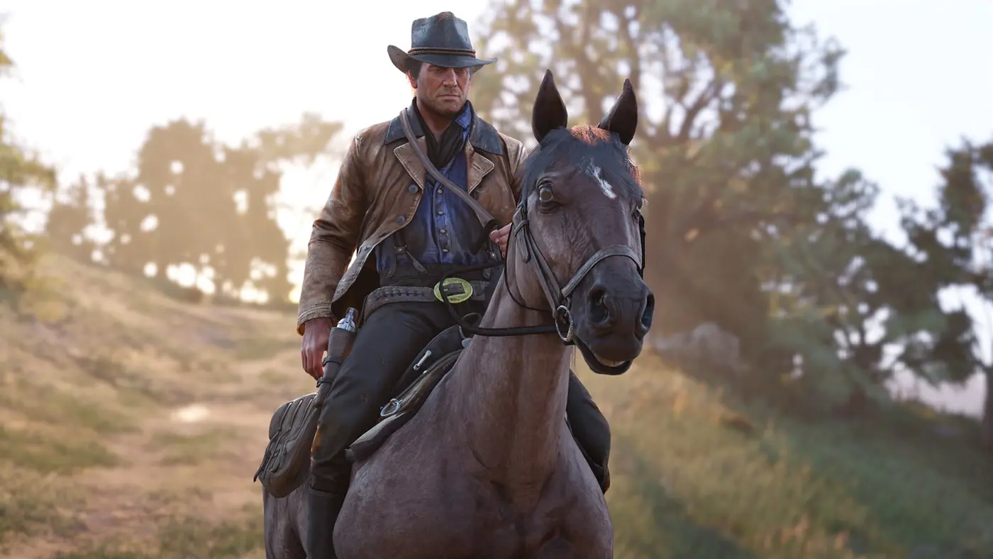 Arthur Morgan sur un cheval bai foncé, veste en cuir et chapeau noir, sur un sentier herbeux baigné de lumière dorée