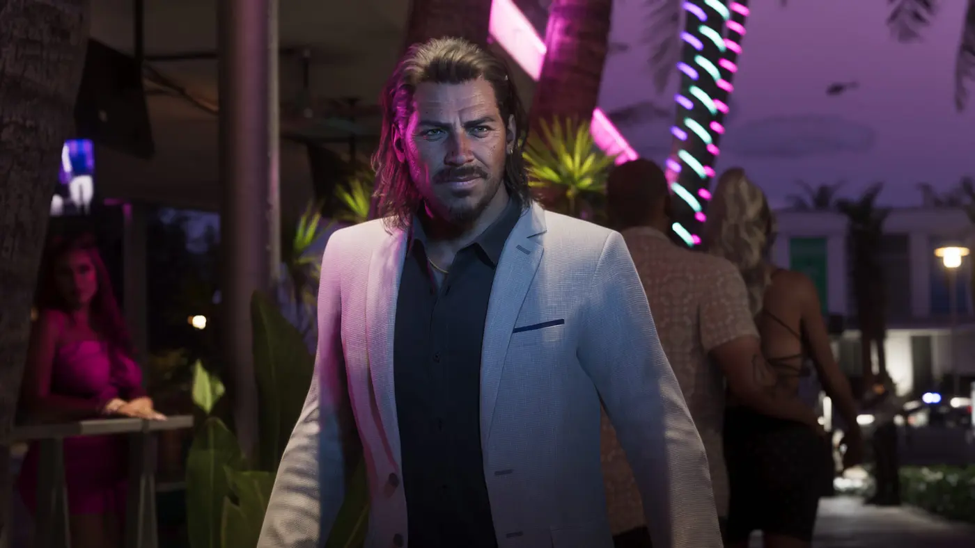 Rue de Vice City la nuit dans GTA VI : un homme en veste claire marche sur un trottoir baigné de néons roses et turquoise, palmiers et passants éclairés par les enseignes lumineuses