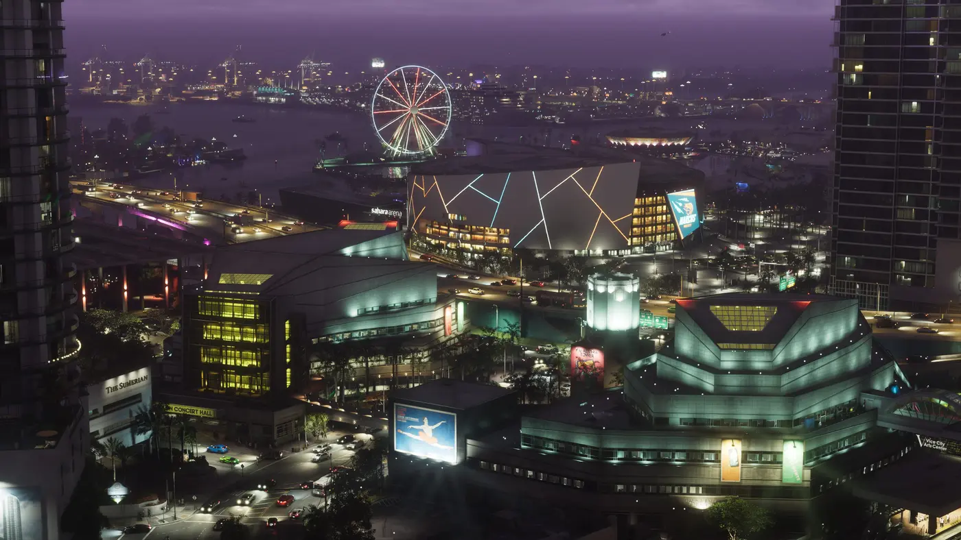 Vue aérienne nocturne du centre de Vice City dans GTA VI : gratte-ciel illuminés, grande roue au bord de l'eau, arène Sahara et front de mer scintillant sous un ciel violet