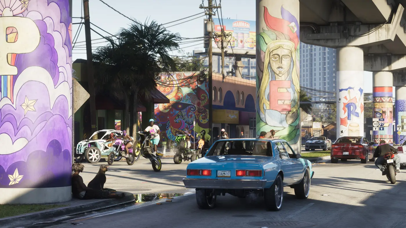 Rue de Vice City dans GTA VI sous une bretelle d'autoroute peinte : une berline lowrider bleue de dos, des motos et un buggy tout-terrain en arrière-plan, voitures garées le long du trottoir