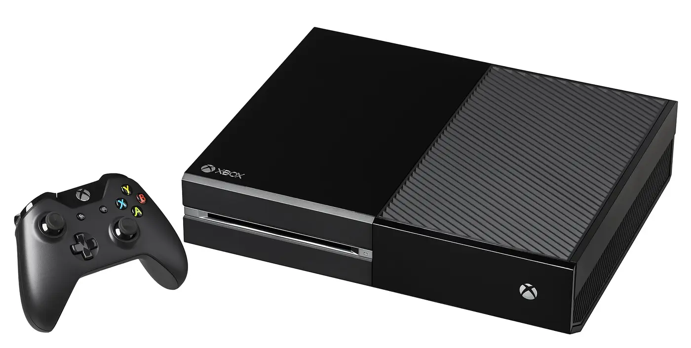 Une Xbox One noire de 2013 posée à l'horizontale avec sa manette noire, sur fond blanc